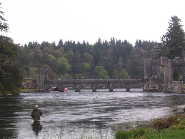 Rybář ve vodě a most ke hradu/hotelu